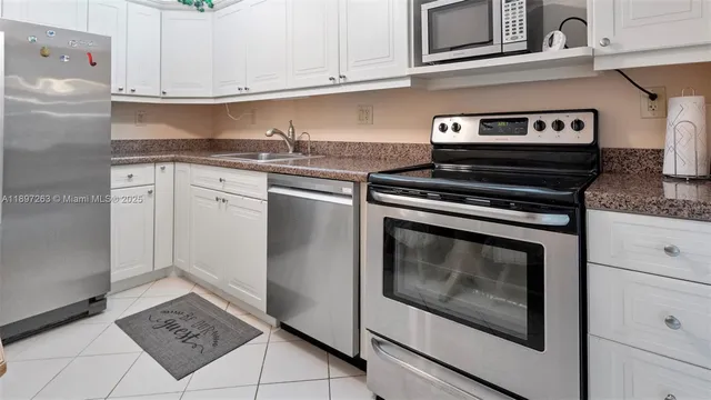 a kitchen with granite countertop white cabinets stainless steel appliances and sink