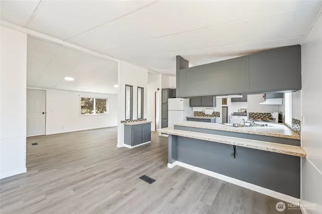 a kitchen with stainless steel appliances granite countertop a sink cabinets and wooden floor