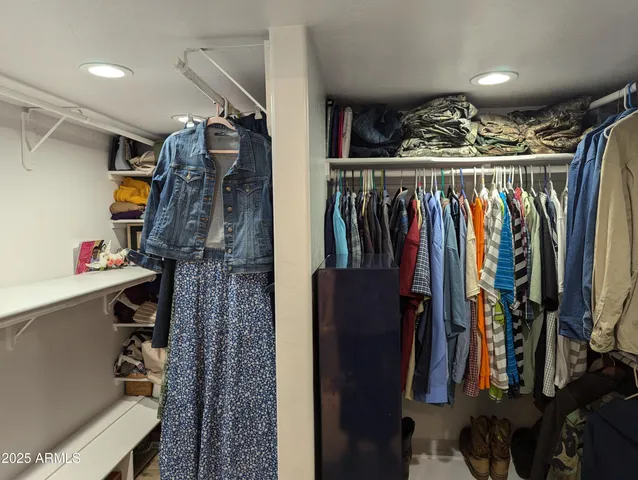 a view of walk in closet with clothes and shoes