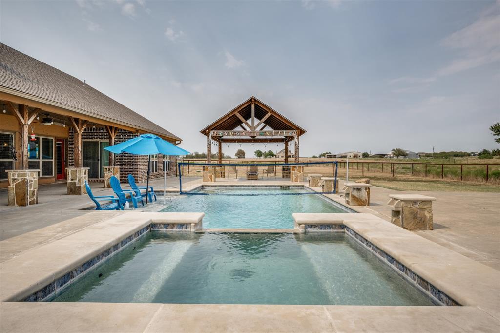 8400 Holder Road Northlake, TX 76247 - Photo 26 of 36 Expansive concrete patio with a built-in swimming pool and spa, featuring stone-clad water features