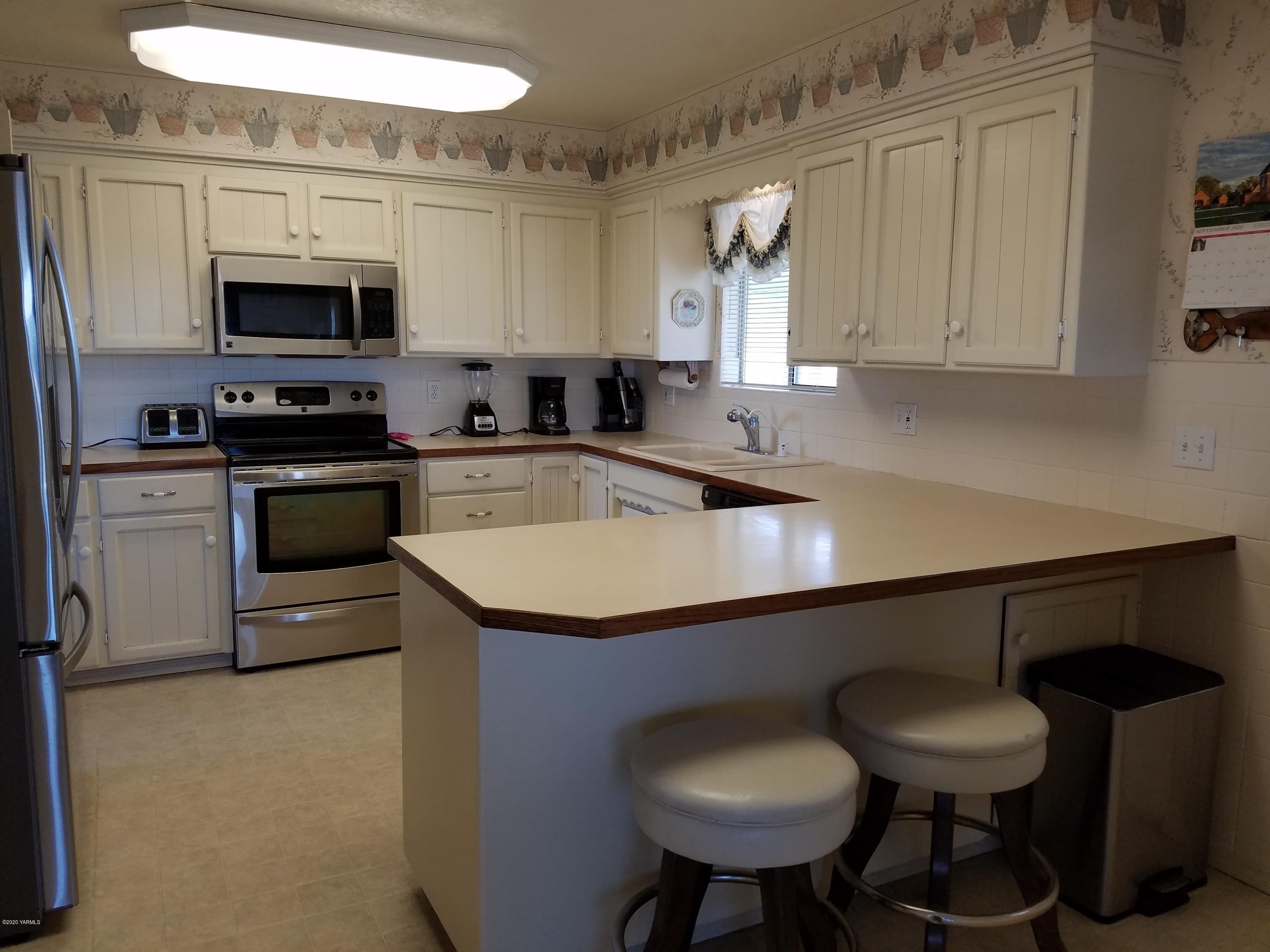30 Wing Hill Road Grandview, WA 98930 - Photo 3 of 27 a kitchen with stainless steel appliances granite countertop a sink dishwasher a stove a microwave oven with cabinets and wooden floor