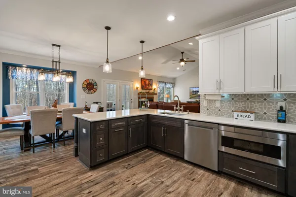 a open kitchen with stainless steel appliances granite countertop a stove and white cabinets with wooden floor