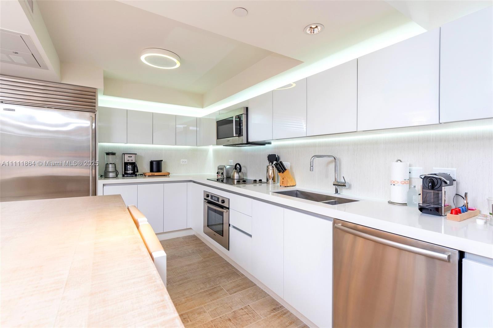 102 24th Street, Unit 906 Miami Beach, FL 33139 - Photo 15 of 15 a kitchen with granite countertop a sink stainless steel appliances and cabinets