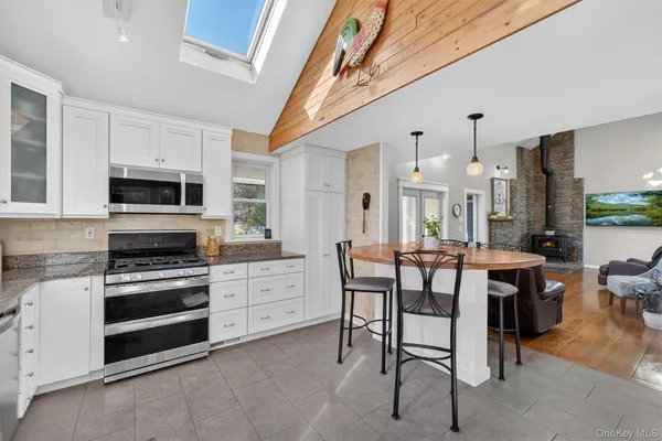 a kitchen with stainless steel appliances granite countertop a stove a sink dishwasher a dining table and chairs with wooden floor