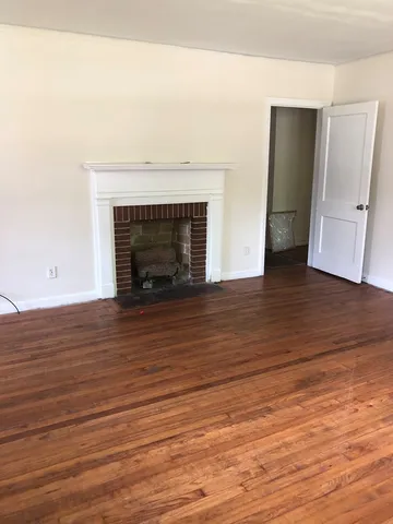 an empty room with wooden floor and fireplace