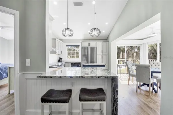 a kitchen with stainless steel appliances granite countertop a stove a kitchen island a dining table and chairs with wooden floor