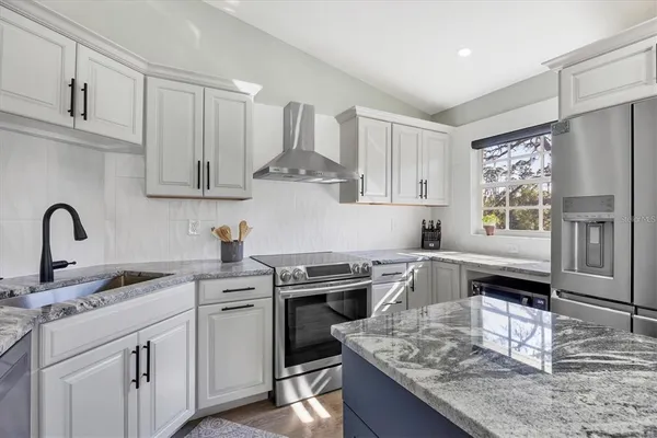a kitchen with kitchen island granite countertop a sink cabinets a stove and stainless steel appliances