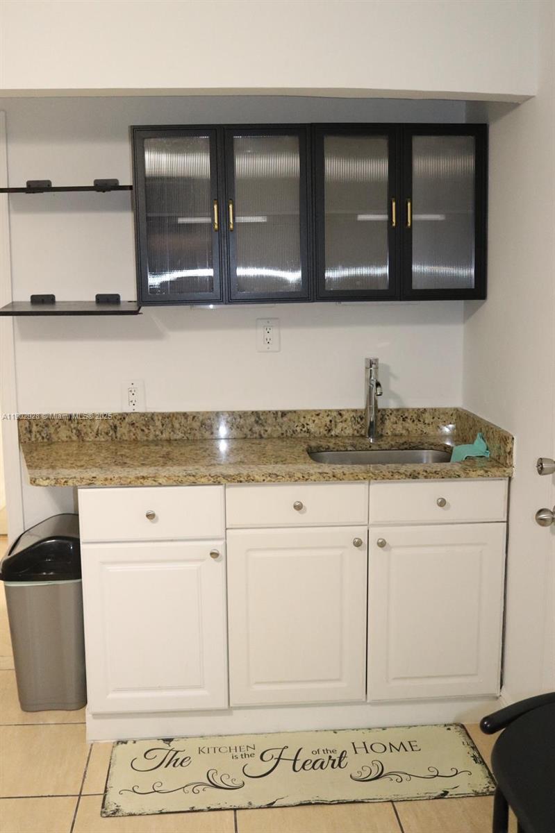 20022 Northwest 58th Court, Unit 1 Hialeah, FL 33015 - Photo 7 of 12 a kitchen with granite countertop white cabinets and a stove