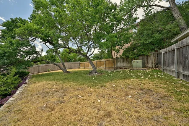 a backyard of a house with lots of plants and tree