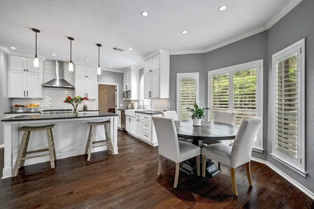 a view of kitchen with stainless steel appliances granite countertop a table chairs sink and cabinets