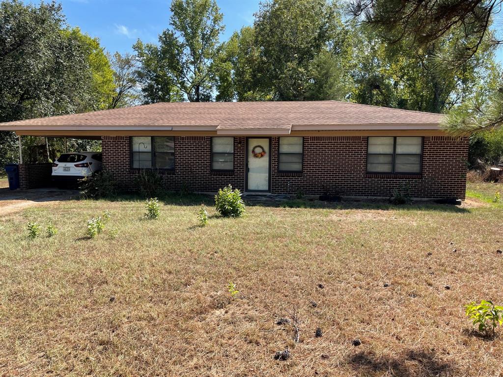 a front view of house with yard and trees in the background
