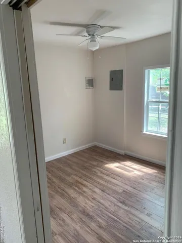 a view of empty room with wooden floor and fan