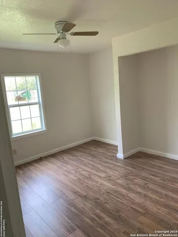 an empty room with wooden floor fan and windows
