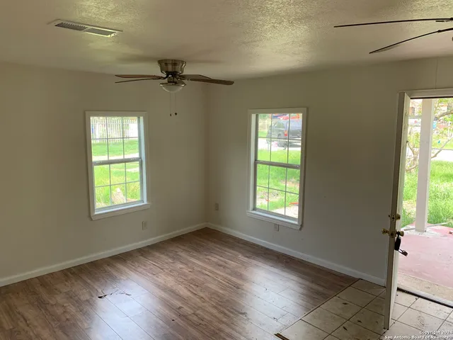 a view of an empty room with a window and wooden floor