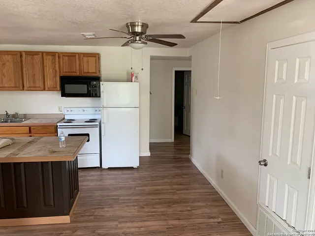 a kitchen with granite countertop a refrigerator a stove top oven a sink and dishwasher with wooden floor