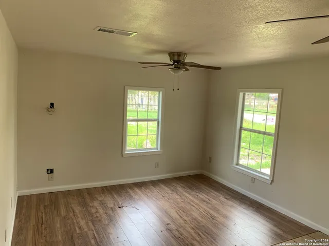 a view of an empty room with a window and wooden floor