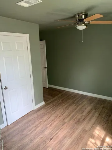 an empty room with wooden floor fan and window