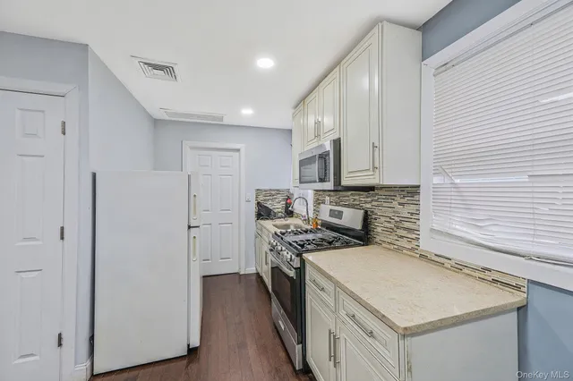 a kitchen with stainless steel appliances granite countertop a refrigerator a stove and a sink