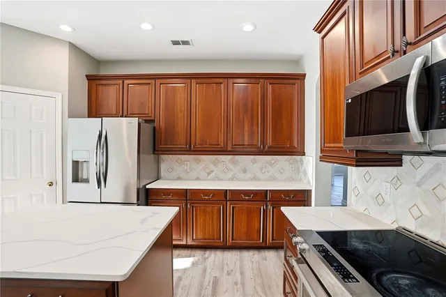 a kitchen with stainless steel appliances granite countertop a refrigerator stove sink and cabinets
