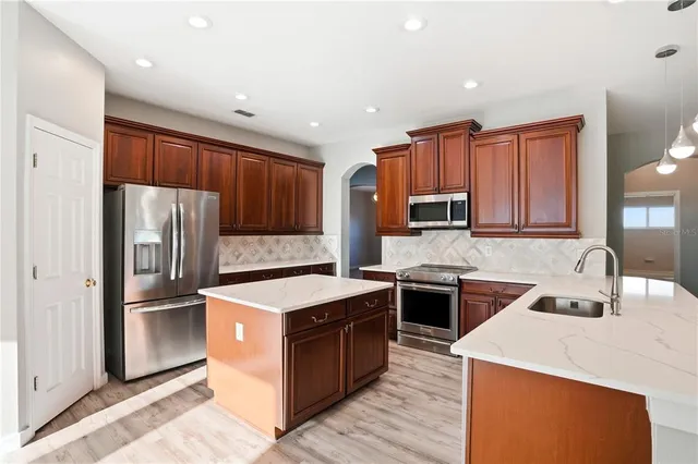 a large kitchen with stainless steel appliances kitchen island granite countertop a stove refrigerator and a sink with large countertops