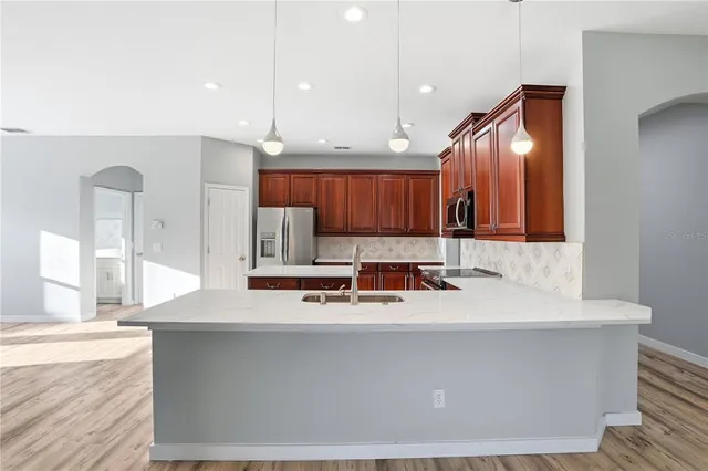 a view of a kitchen and an empty room with wooden floor