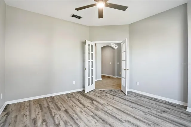 an empty room with wooden floor fan and windows