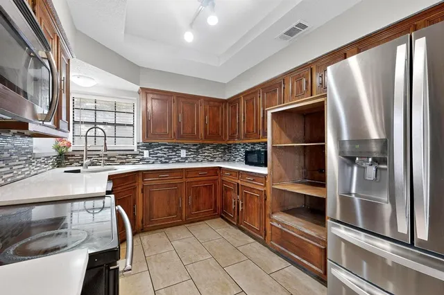 a kitchen with stainless steel appliances granite countertop a refrigerator and wooden cabinets