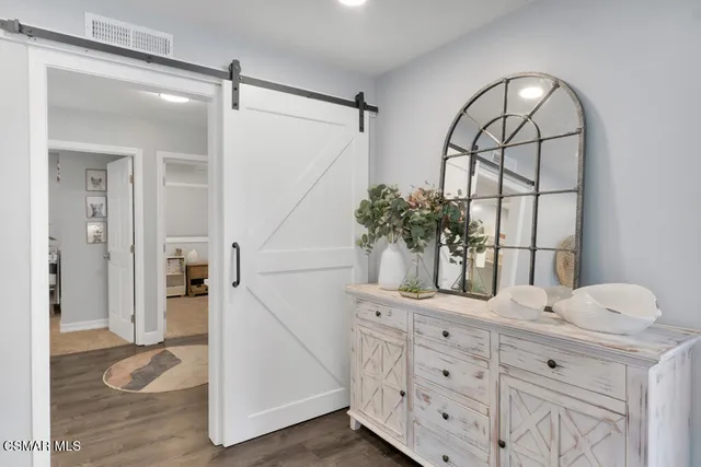 a kitchen with stainless steel appliances white cabinets a sink a stove a refrigerator and microwave with wooden floor