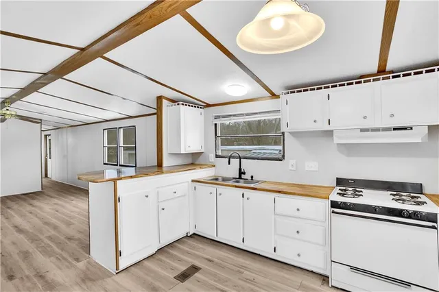 a kitchen with granite countertop a sink a stove and cabinets