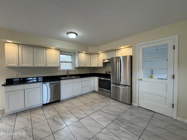 a kitchen with granite countertop a refrigerator and a stove top oven