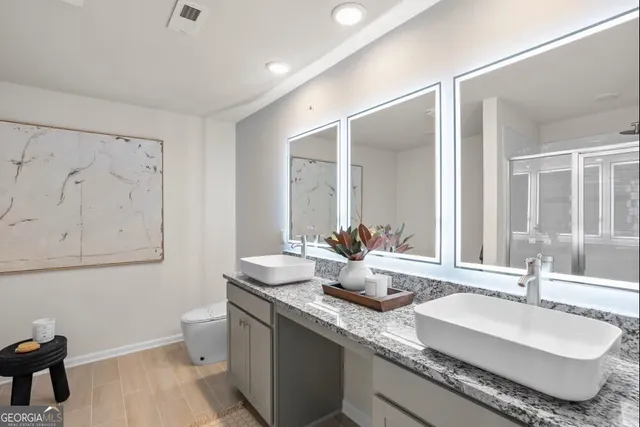 a bathroom with double vanity sinks a mirror and a toilet