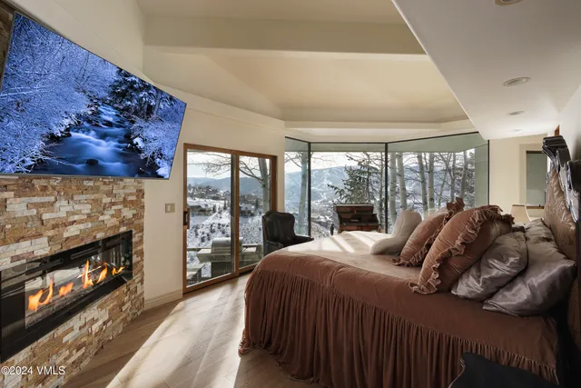 a bedroom with a bed a fireplace and a large window