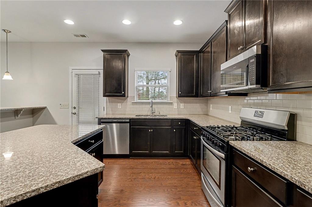 321 Lara Lane Hampton, GA 30228 - Photo 10 of 33 a kitchen with stainless steel appliances granite countertop wooden cabinets a stove top oven and granite counter tops