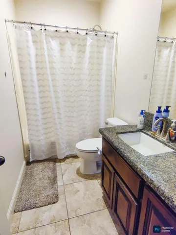 a bathroom with a granite countertop sink and a toilet