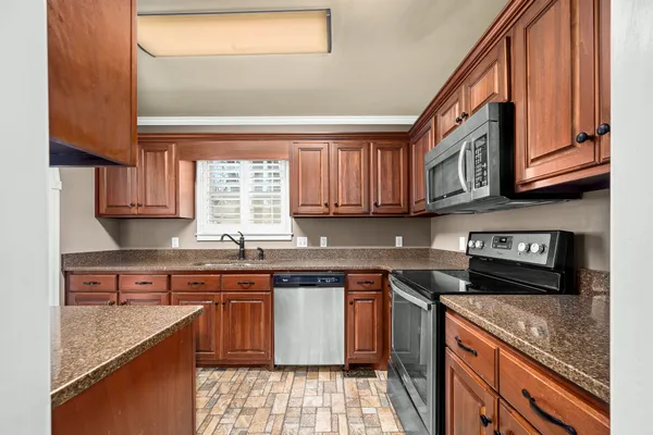 a kitchen with granite countertop stainless steel appliances a sink and cabinets