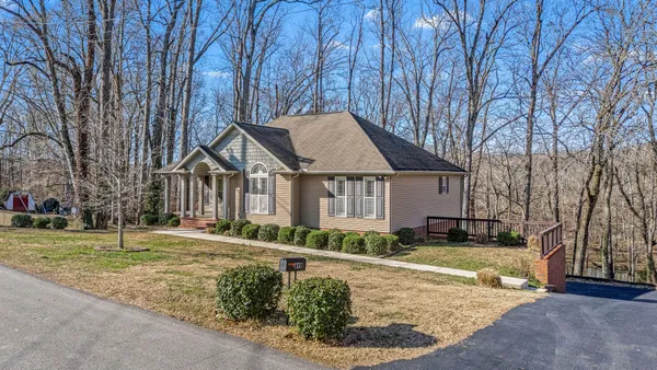 a view of a white house with a yard and large tree