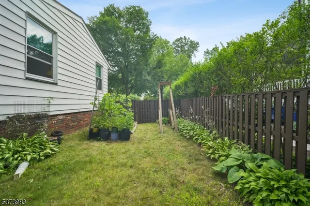 a view of a backyard with plants and wooden fence