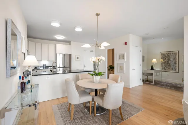a kitchen with stainless steel appliances kitchen island granite countertop a dining table chairs and white cabinets