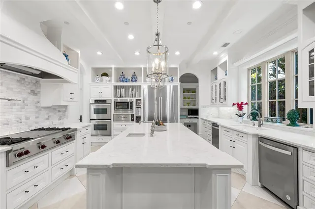 a kitchen with stainless steel appliances a chandelier open stove top oven