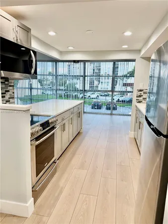 a large kitchen with kitchen island a sink stove and wooden floor