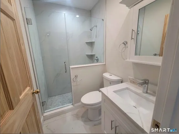 a bathroom with a sink a toilet a mirror and shower