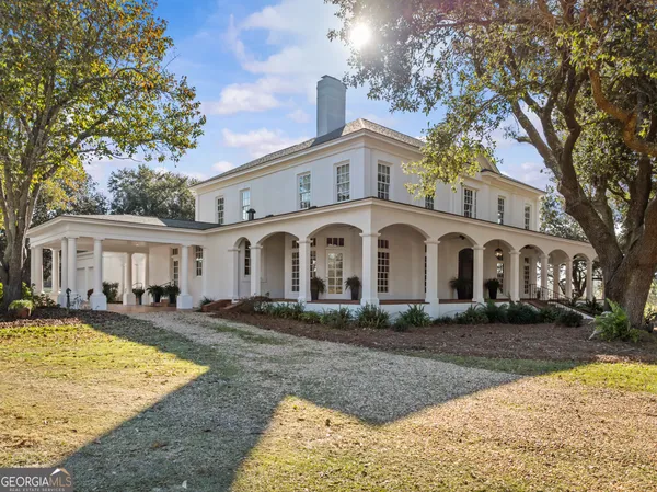 a view of a white house with a large tree