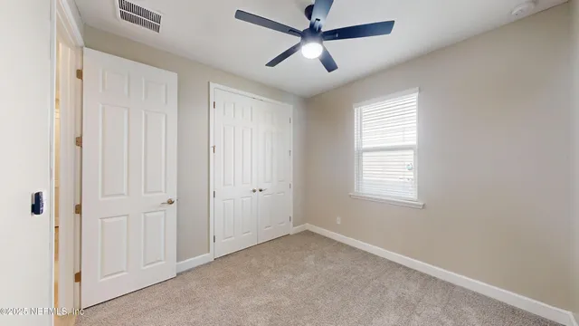 a view of a livingroom with a ceiling fan & windows
