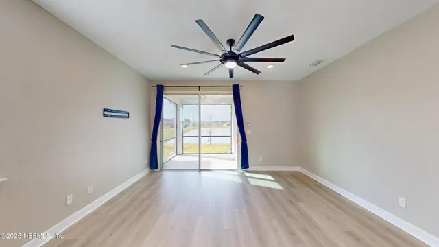 an empty room with wooden floor fan and windows