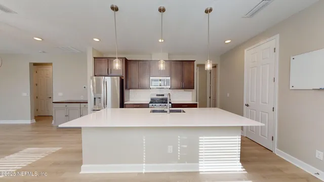 a view of kitchen with refrigerator stove and wooden floor