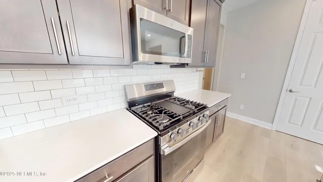 a kitchen with granite countertop a stove and a white cabinets