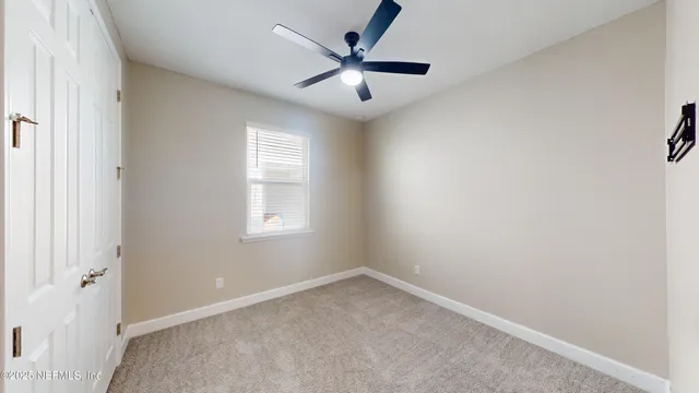 an empty room with windows and fan