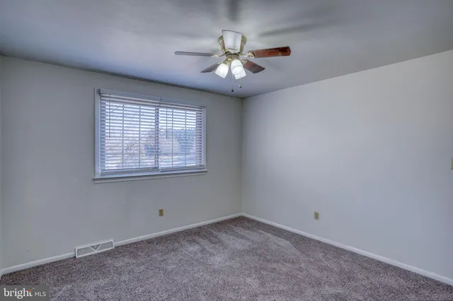 an empty room with a window and a ceiling fan