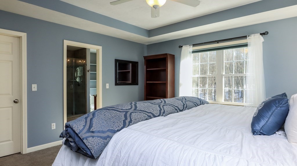 85 Dudley Road, Unit 85 Berlin, MA 01503 - Photo 18 of 39 a bedroom with a large bed and a chandelier