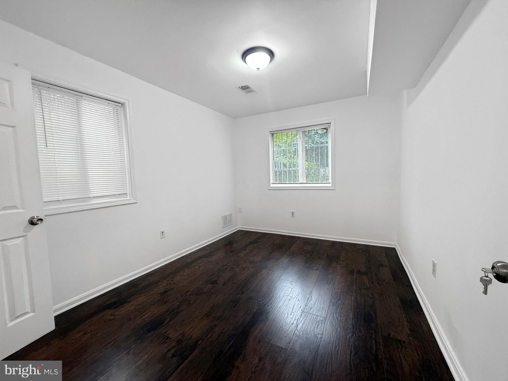506 Eastern Avenue Northeast, Unit 102 Washington, DC 20019 - Photo 5 of 13 an empty room with wooden floor and windows